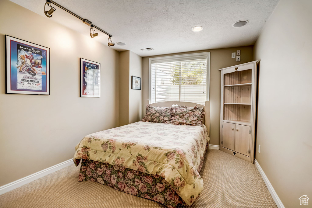 Bedroom with carpet flooring, track lighting, and a textured ceiling