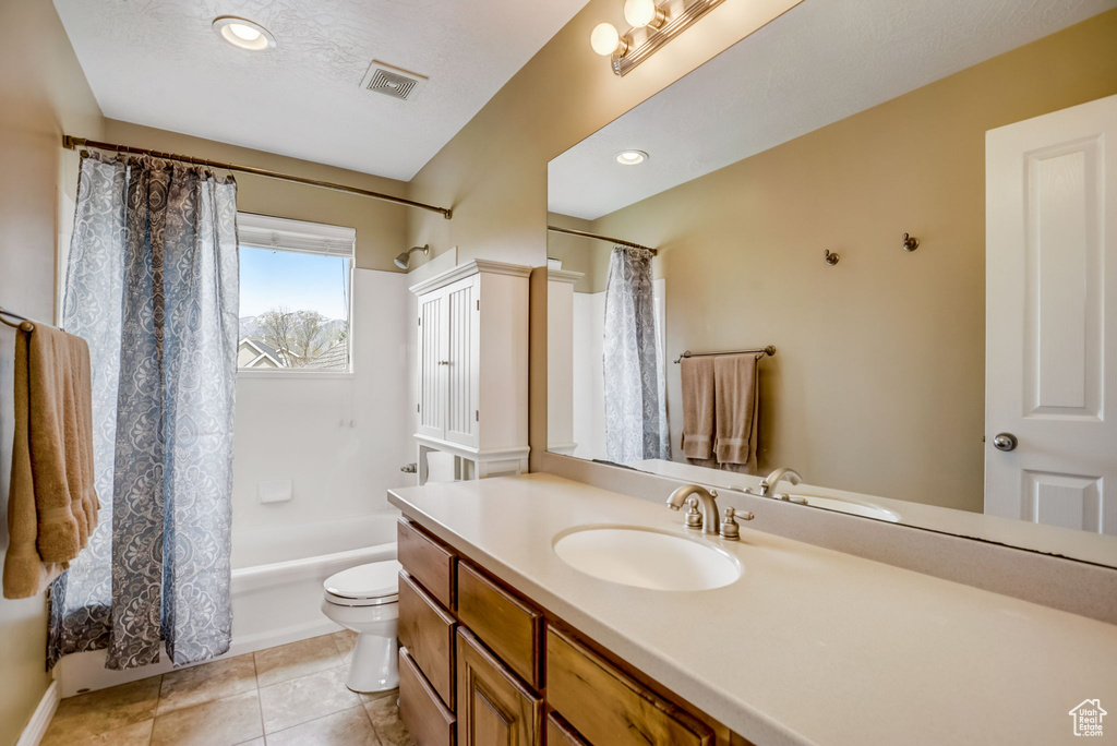 Full bathroom featuring shower / bath combination with curtain, vanity with extensive cabinet space, toilet, and tile flooring