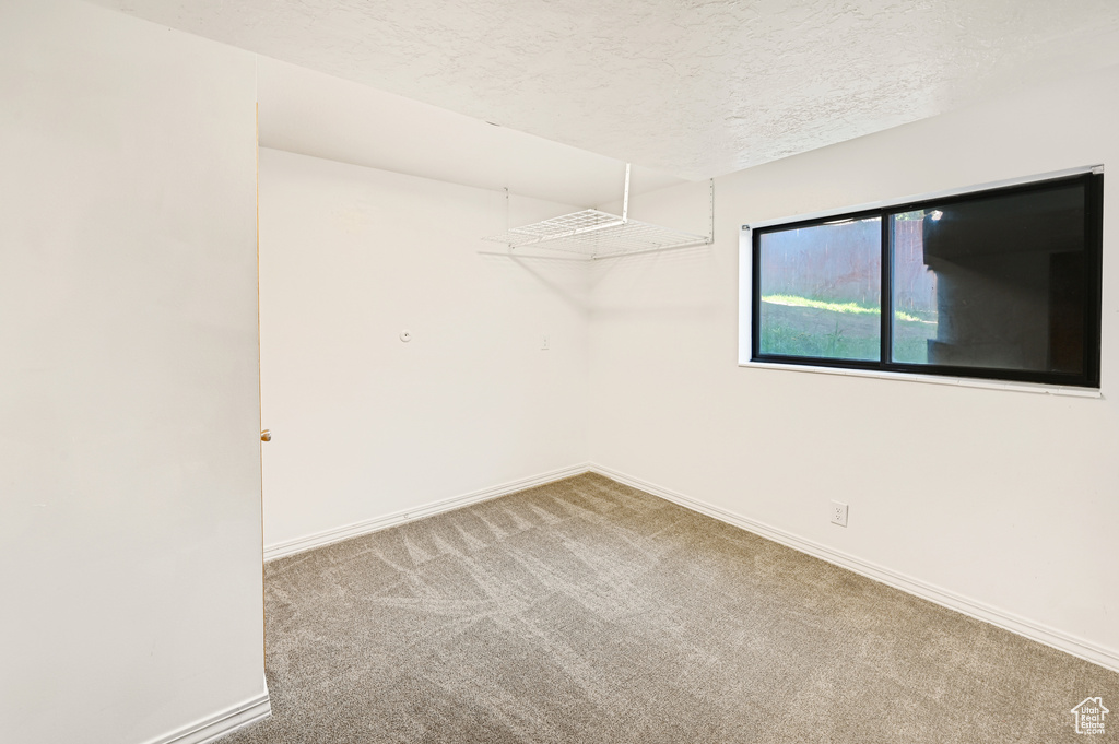 Unfurnished room with a textured ceiling and carpet flooring