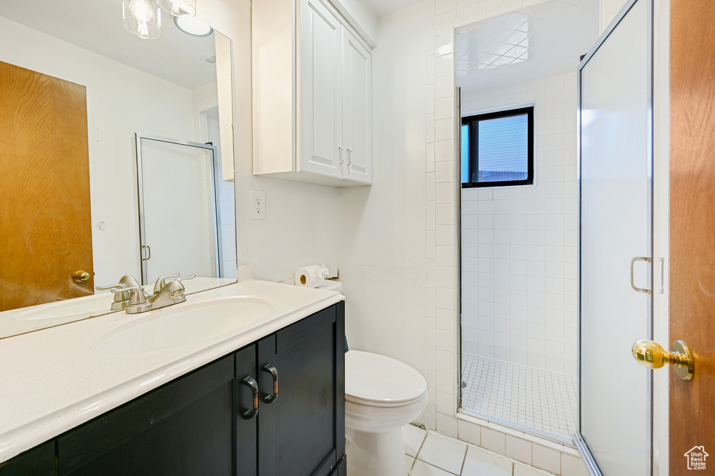 Bathroom with tile floors, toilet, oversized vanity, and a shower with shower door