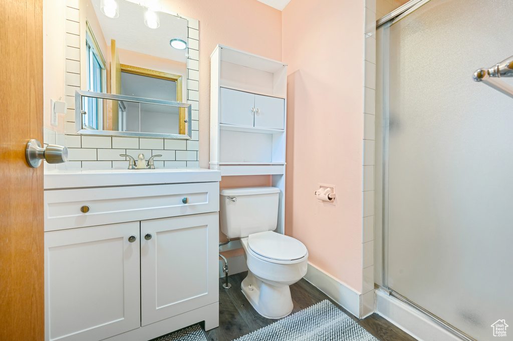 Bathroom with vanity, hardwood / wood-style floors, backsplash, a shower with shower door, and toilet