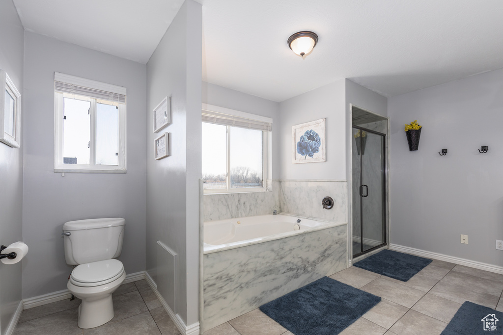 Bathroom with a wealth of natural light, shower with separate bathtub, toilet, and tile floors