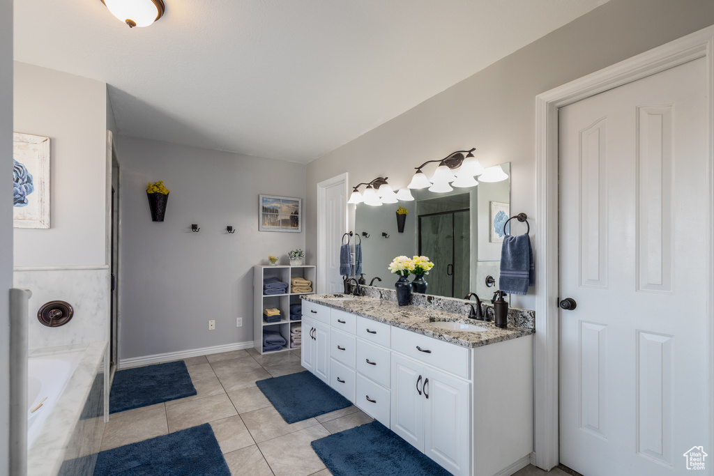 Bathroom featuring vanity with extensive cabinet space, double sink, tile flooring, and a bath