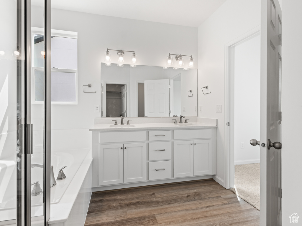 Bathroom with dual bowl vanity, hardwood / wood-style flooring, and a bathtub