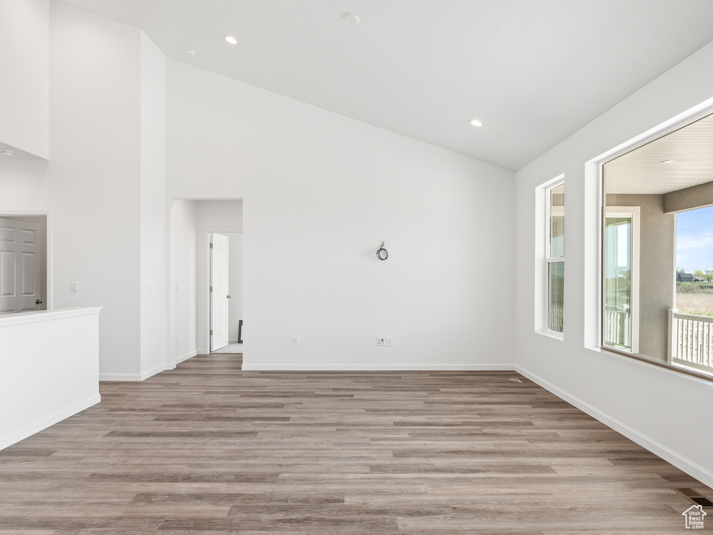 Empty room featuring high vaulted ceiling and hardwood / wood-style flooring