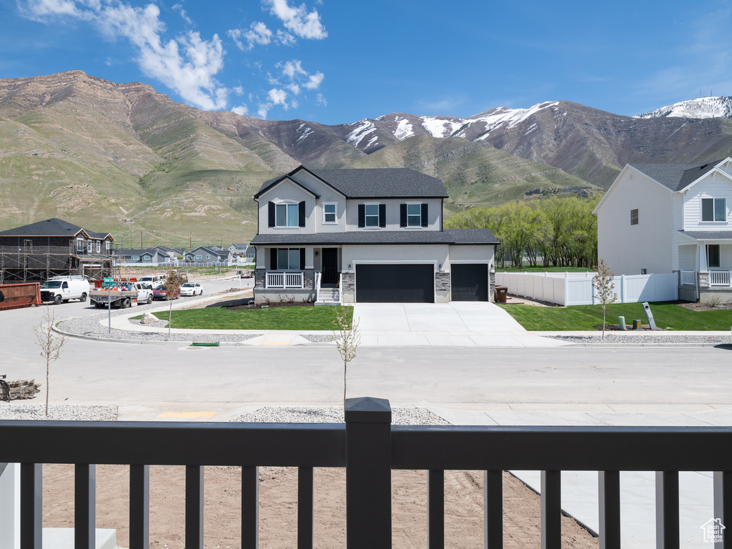 Exterior space with a mountain view, a garage, and a front lawn