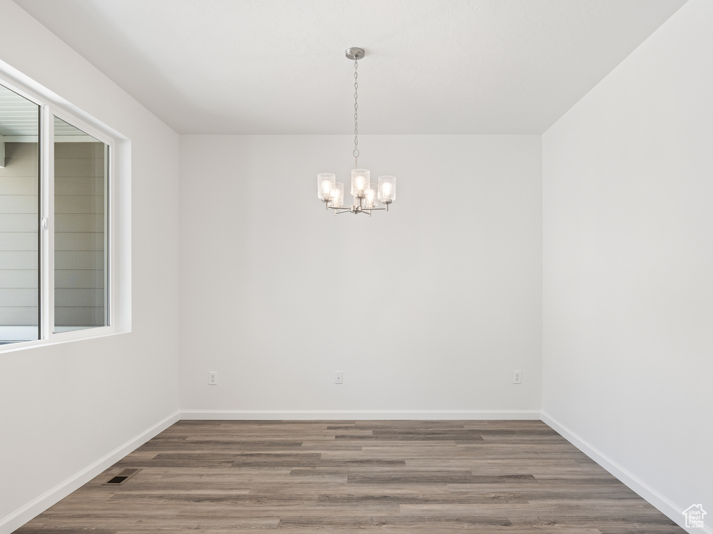 Empty room with an inviting chandelier and hardwood / wood-style floors