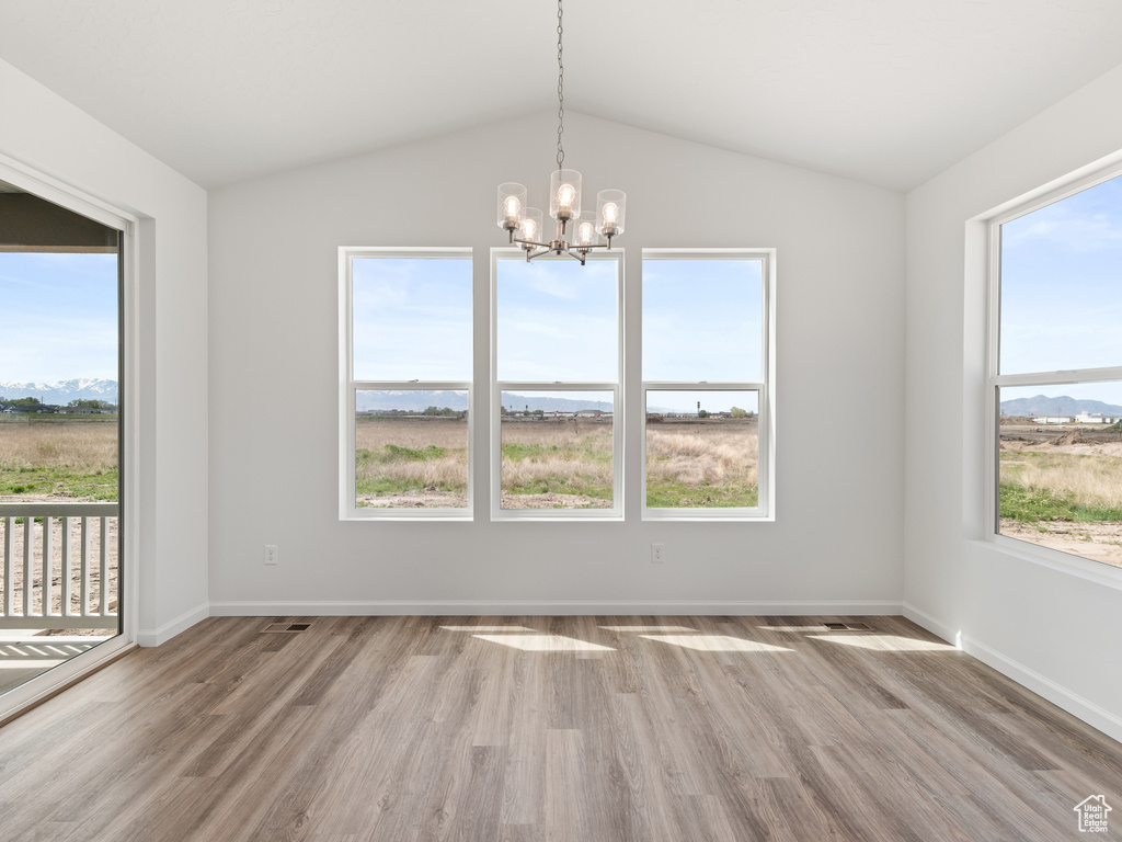 Unfurnished room featuring plenty of natural light, hardwood / wood-style floors, and vaulted ceiling