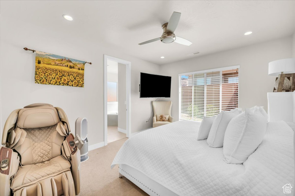 Bedroom featuring light carpet, ceiling fan, and ensuite bathroom