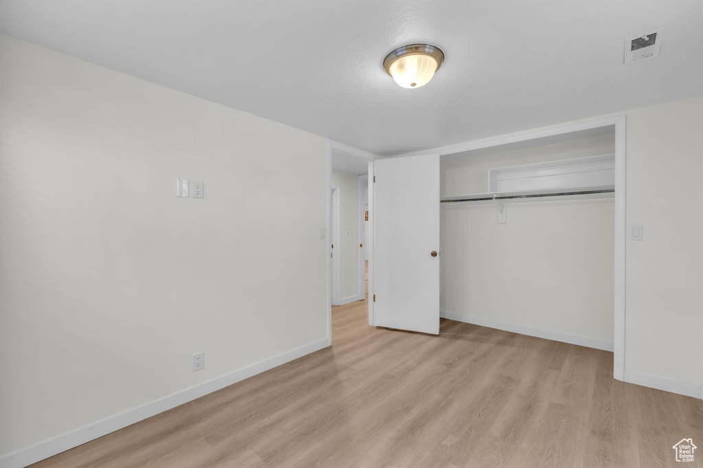 Unfurnished bedroom with light hardwood / wood-style floors and a closet