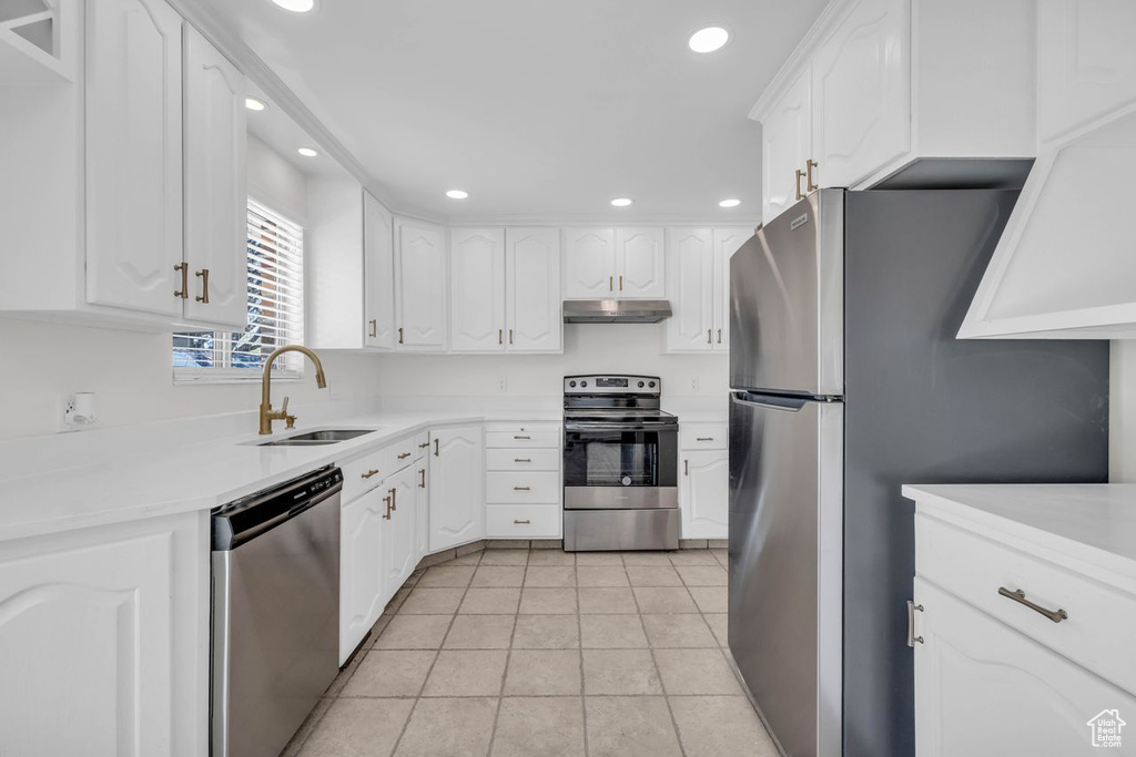 Kitchen featuring white cabinetry, stainless steel appliances, light tile floors, and sink