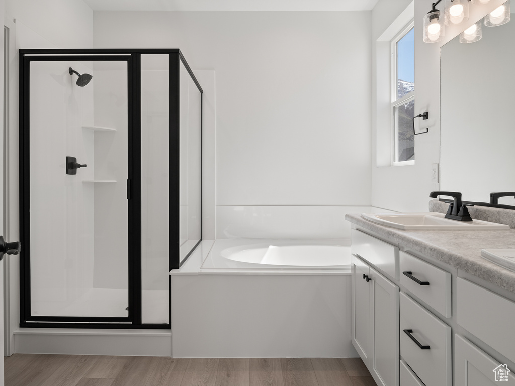 Bathroom with double vanity, separate shower and tub, and hardwood / wood-style flooring