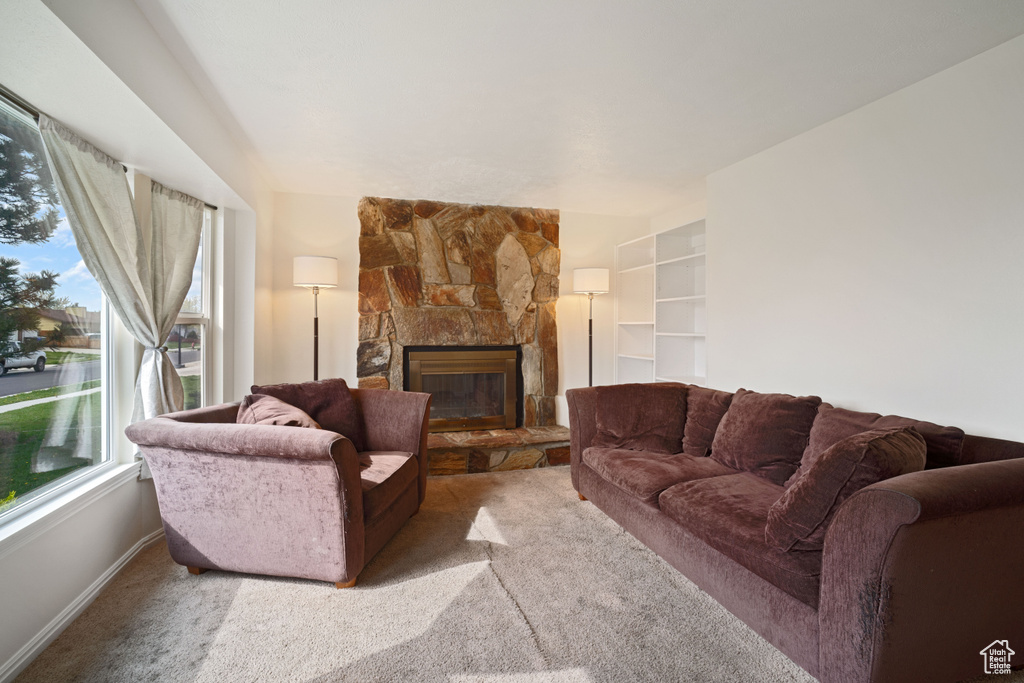 Carpeted living room featuring a stone fireplace