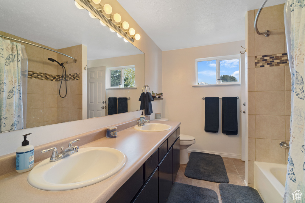 Full bathroom featuring oversized vanity, shower / bathtub combination with curtain, toilet, double sink, and tile floors