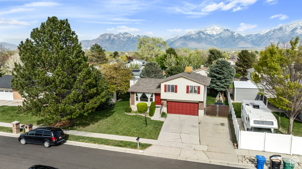 View of front of house with a garage, a mountain view, and a front yard