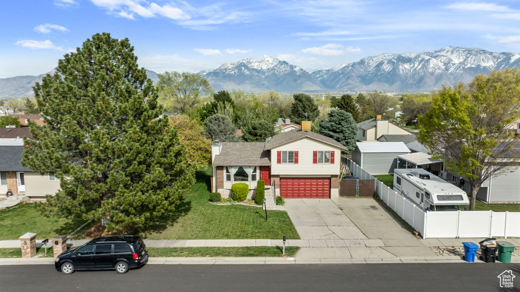 View of front of house featuring a front yard, a mountain view, and a garage