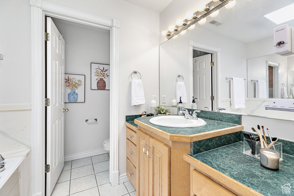 Bathroom with tile floors, toilet, and vanity with extensive cabinet space