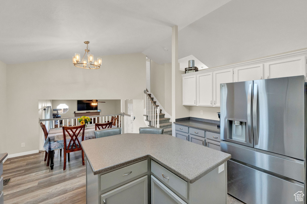 Kitchen featuring a center island, hanging light fixtures, high vaulted ceiling, stainless steel refrigerator with ice dispenser, and light hardwood / wood-style floors