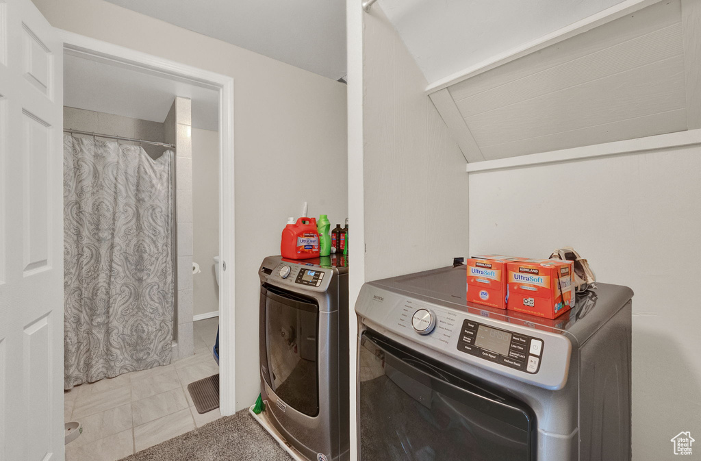 Clothes washing area with light tile flooring and washer and clothes dryer