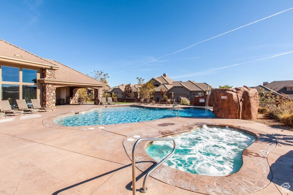 View of swimming pool featuring a community hot tub and a patio area