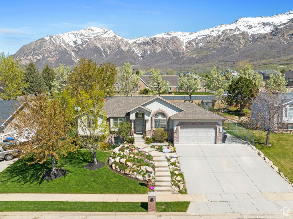 Ranch-style house featuring a mountain view, a garage, and a front lawn