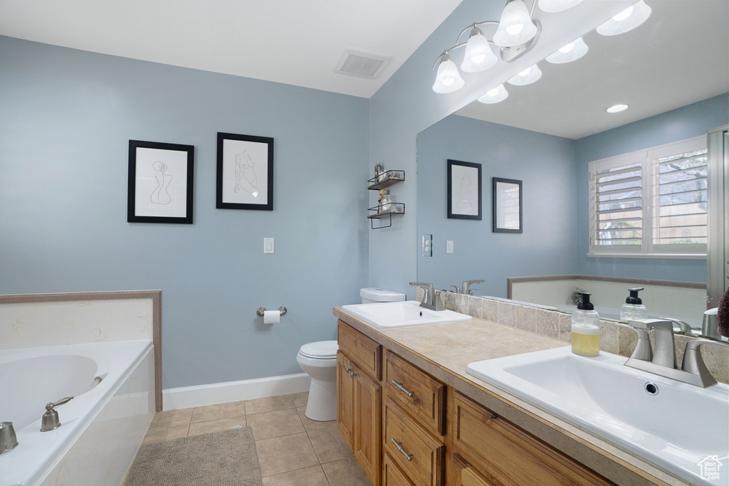 Bathroom with vanity with extensive cabinet space, toilet, double sink, a tub, and tile floors