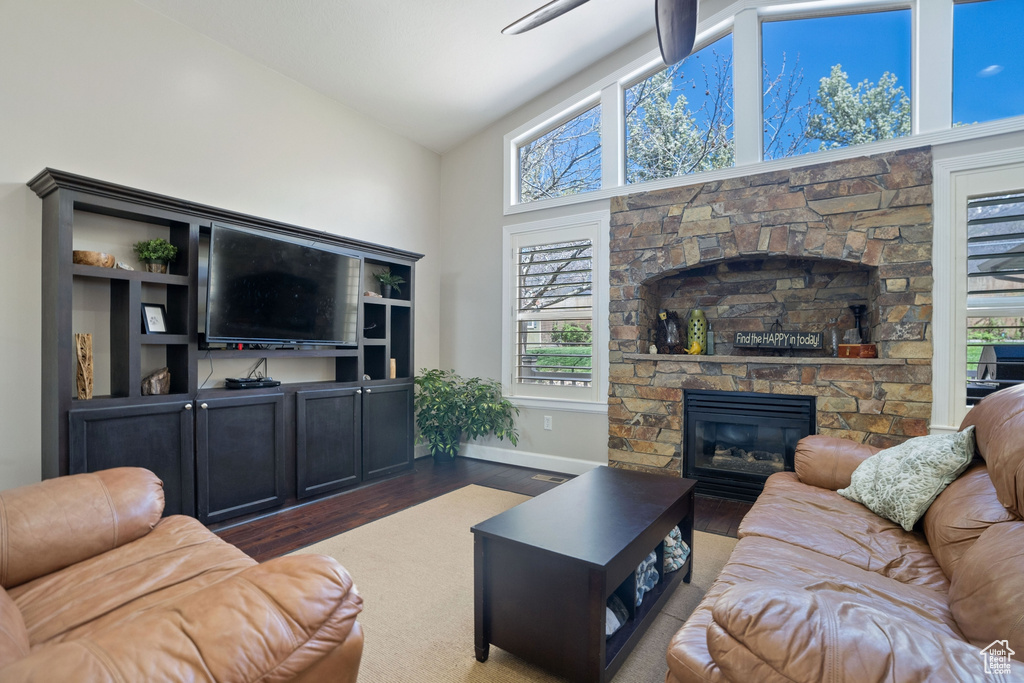 Living room featuring a wealth of natural light, dark hardwood / wood-style flooring, beamed ceiling, and a fireplace