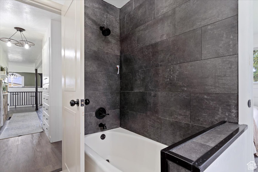 Bathroom with hardwood / wood-style flooring, crown molding, tiled shower / bath, and vanity