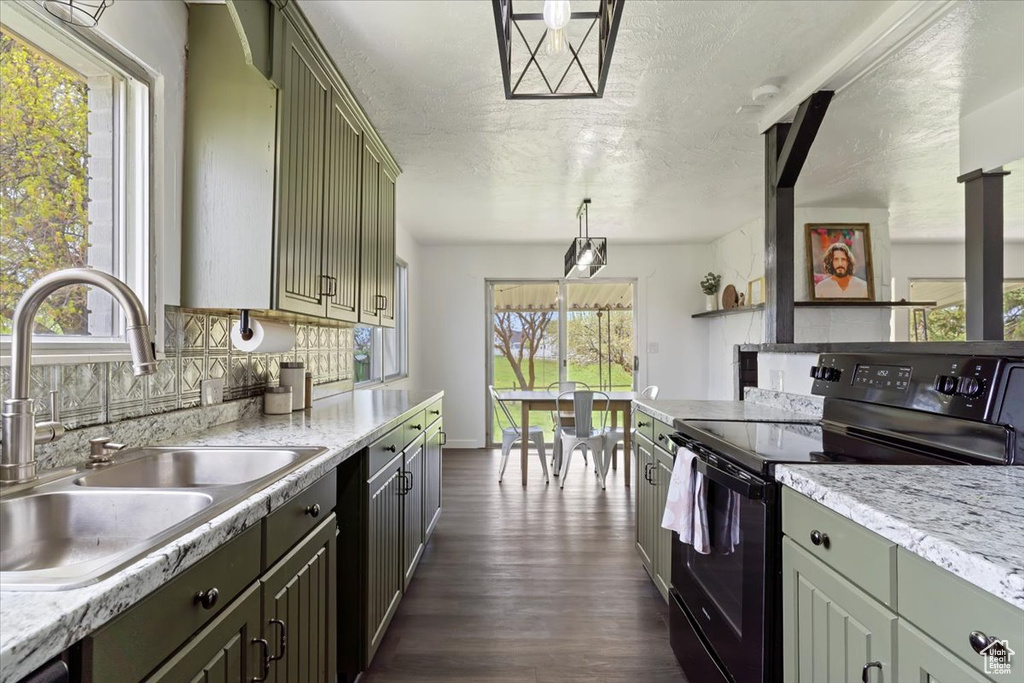 Kitchen with decorative light fixtures, dark wood-type flooring, backsplash, sink, and black / electric stove