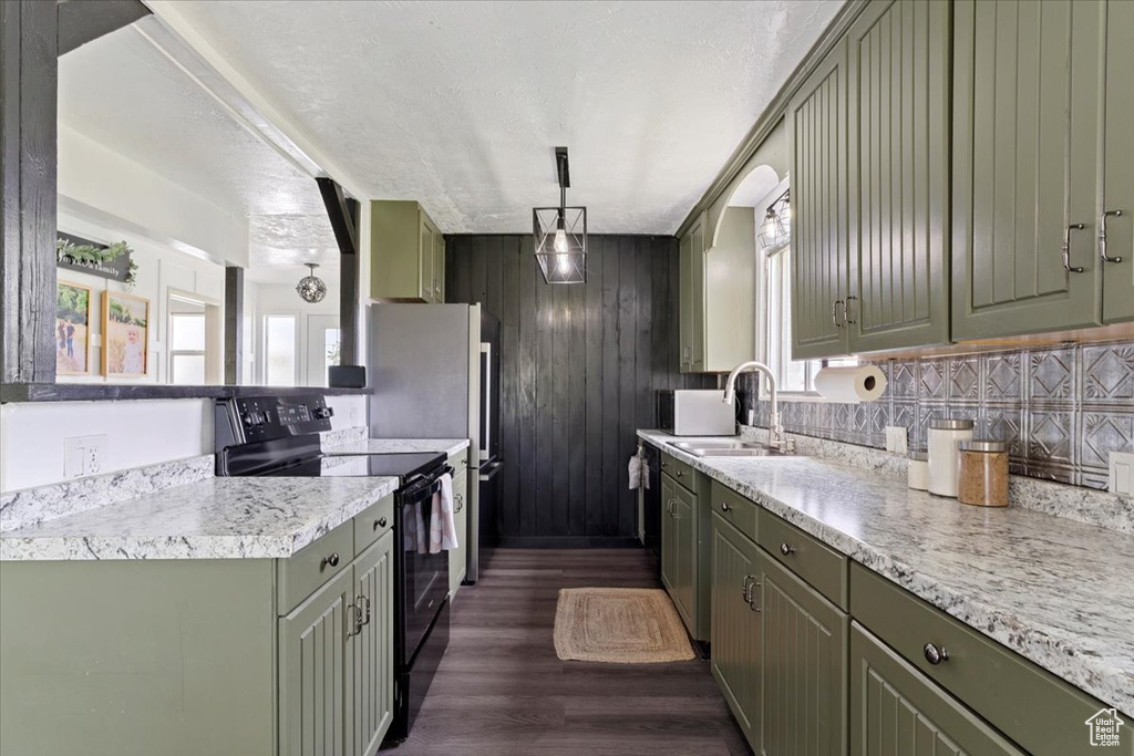 Kitchen with pendant lighting, black range with electric cooktop, dark hardwood / wood-style floors, green cabinets, and sink