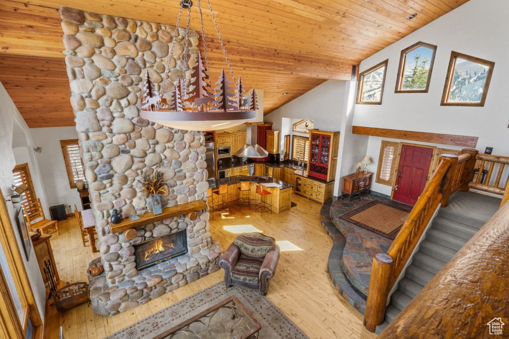 Living room with hardwood / wood-style floors, a stone fireplace, high vaulted ceiling, and wood ceiling
