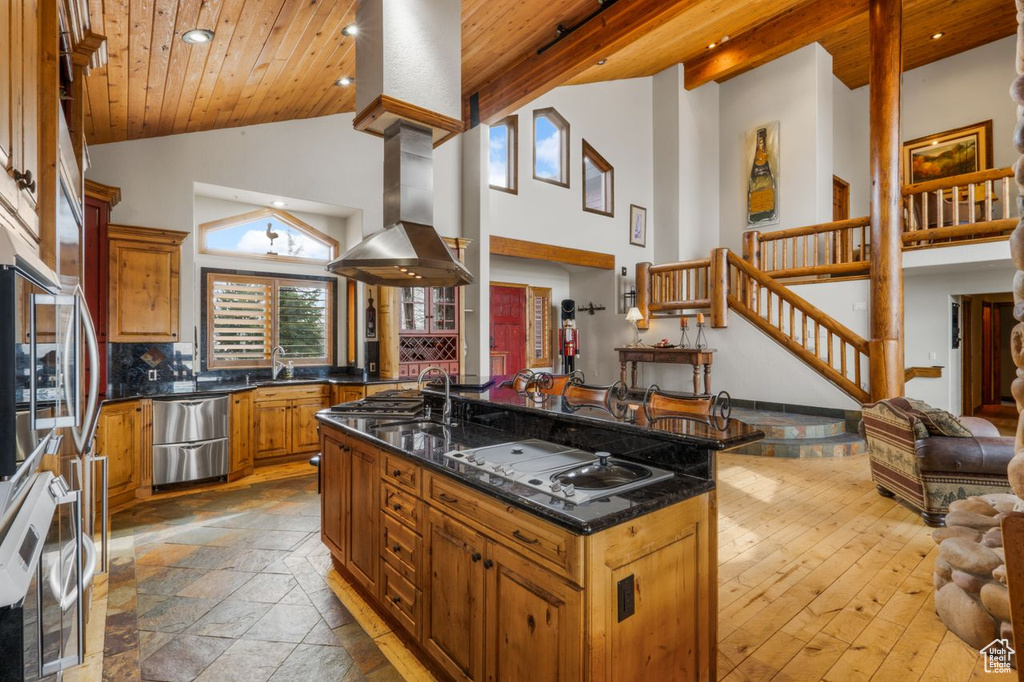 Kitchen with a kitchen island with sink, island exhaust hood, light hardwood / wood-style flooring, wood ceiling, and tasteful backsplash