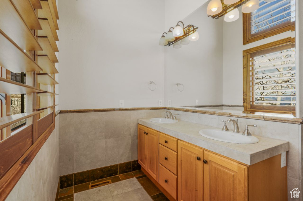 Bathroom with tile flooring, tile walls, double sink, and vanity with extensive cabinet space