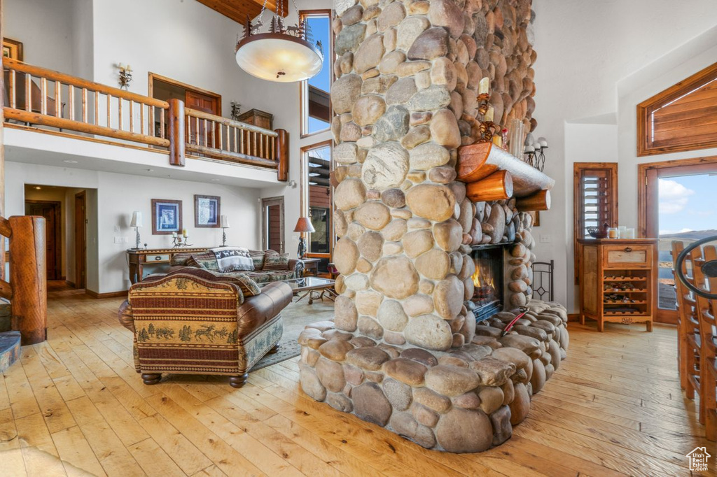Living room with a stone fireplace, a high ceiling, and hardwood / wood-style floors