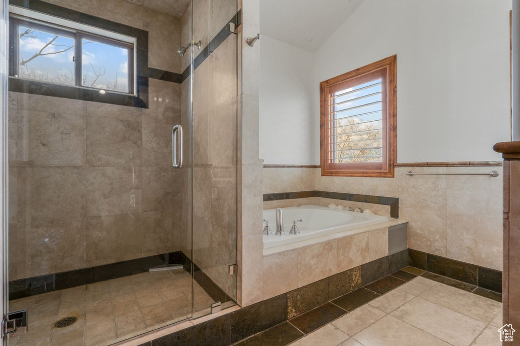 Bathroom featuring vaulted ceiling, a healthy amount of sunlight, and separate shower and tub