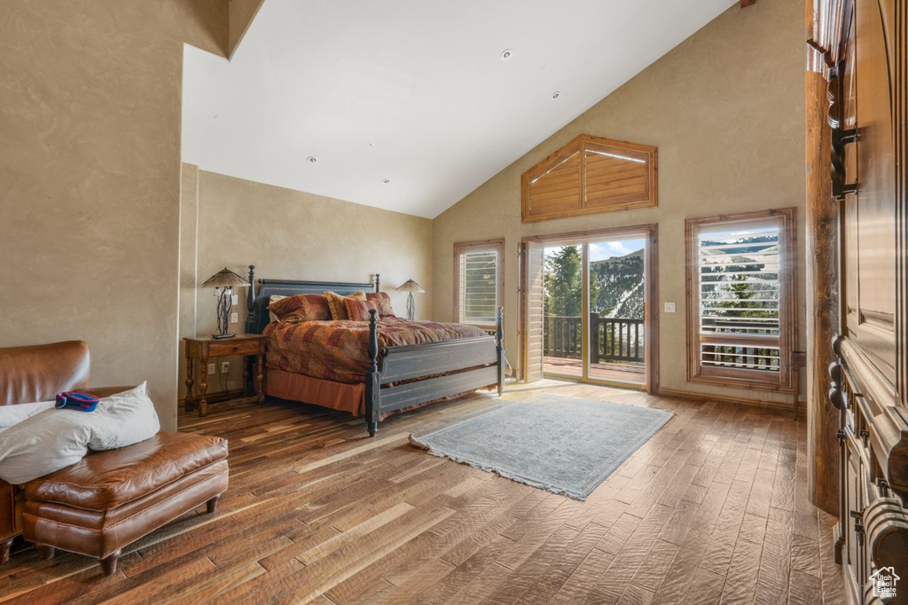 Bedroom with wood-type flooring, high vaulted ceiling, and access to exterior