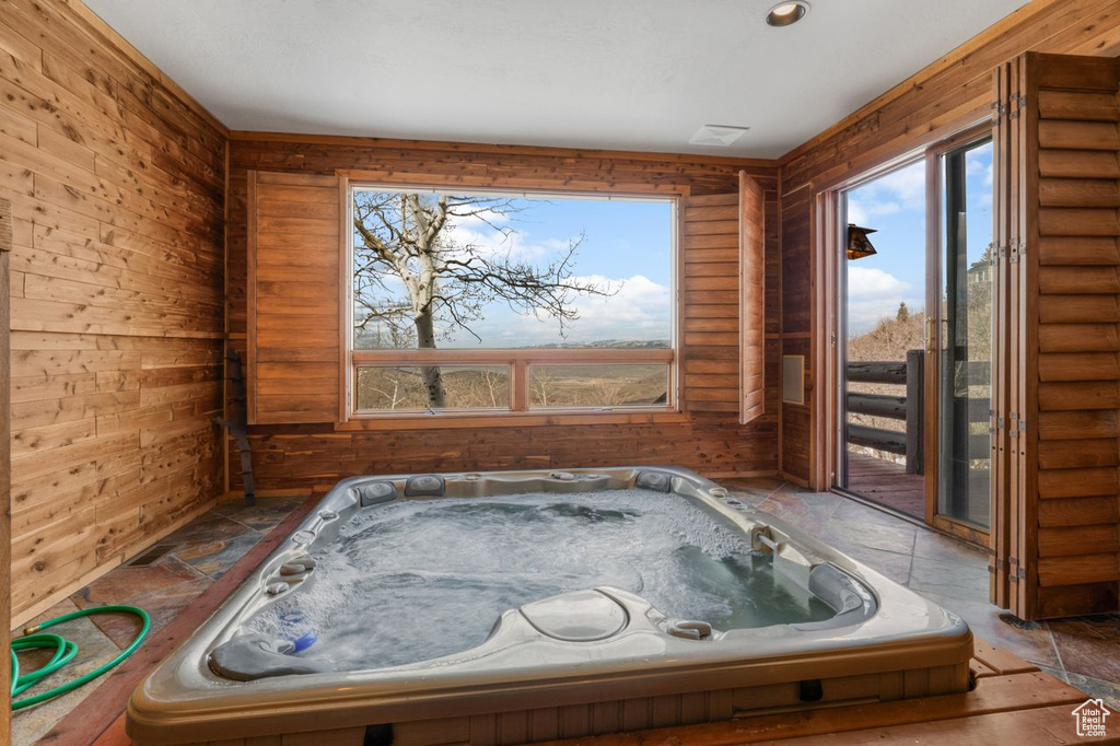 Misc room featuring a wealth of natural light, a hot tub, and wooden walls