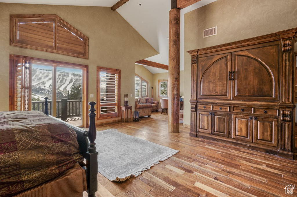 Bedroom with a mountain view, access to outside, high vaulted ceiling, hardwood / wood-style floors, and beam ceiling