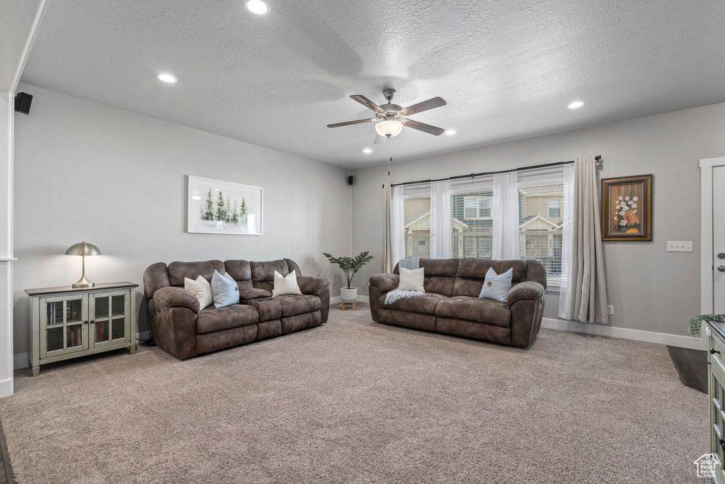 Living room featuring light colored carpet, a textured ceiling, and ceiling fan