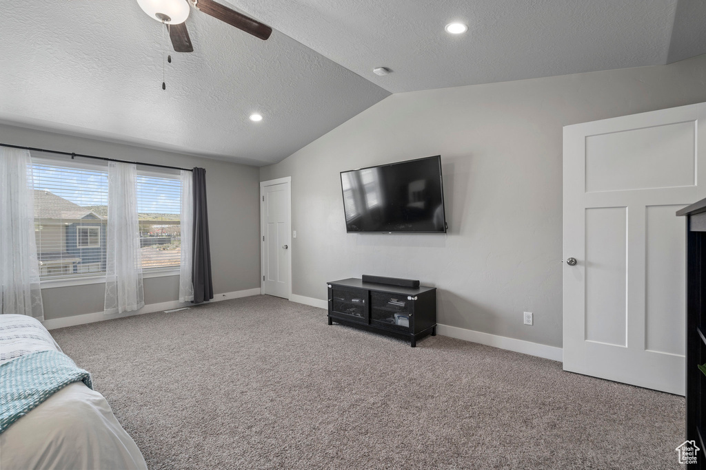 Bedroom with vaulted ceiling, ceiling fan, light carpet, and a textured ceiling
