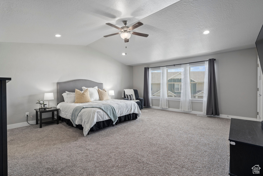 Bedroom featuring lofted ceiling, ceiling fan, carpet flooring, and a textured ceiling