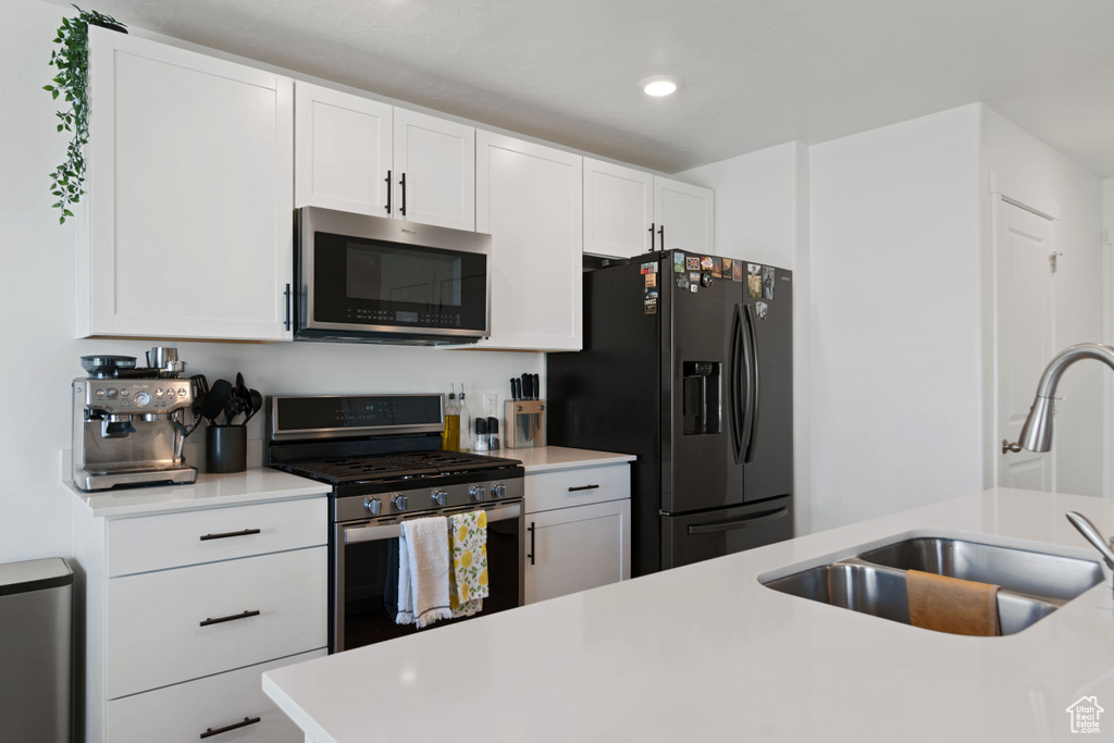 Kitchen with white cabinets, sink, and stainless steel appliances