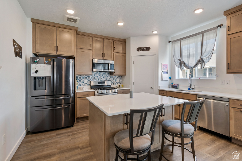 Kitchen featuring hardwood / wood-style floors, sink, appliances with stainless steel finishes, and a center island