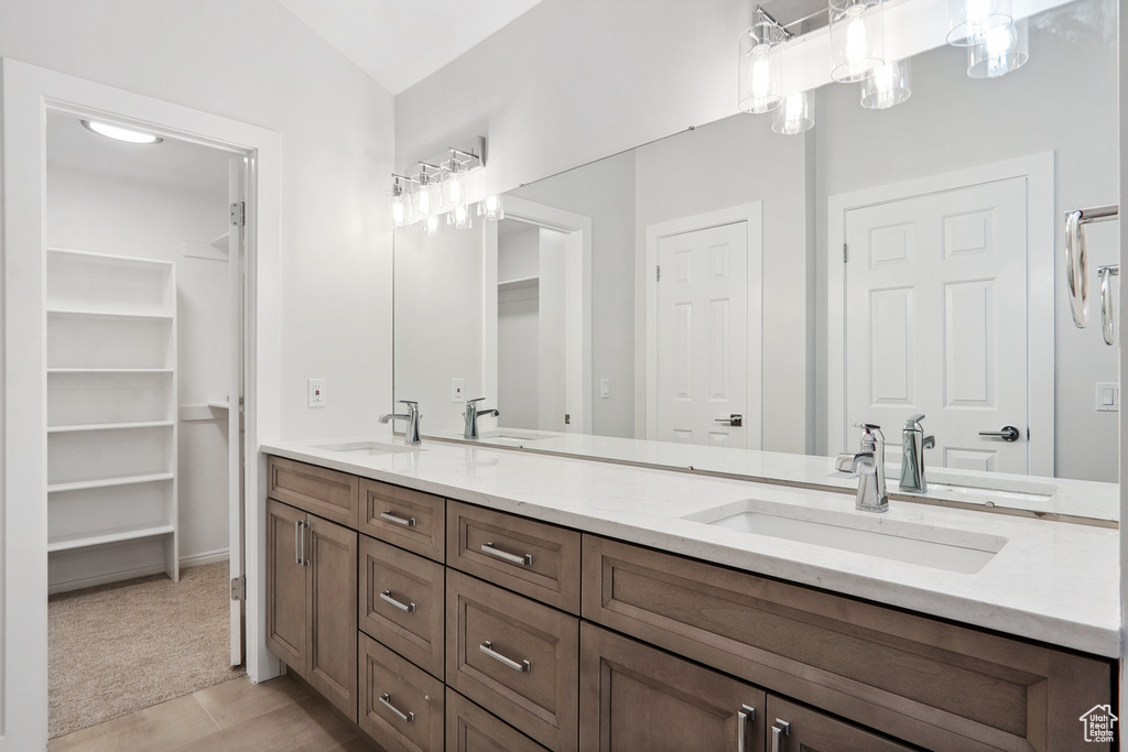 Bathroom with vanity with extensive cabinet space, double sink, tile floors, and vaulted ceiling