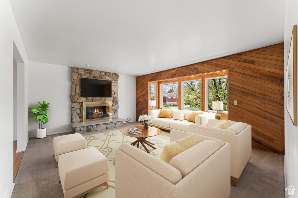 Carpeted living room featuring a fireplace and wood walls