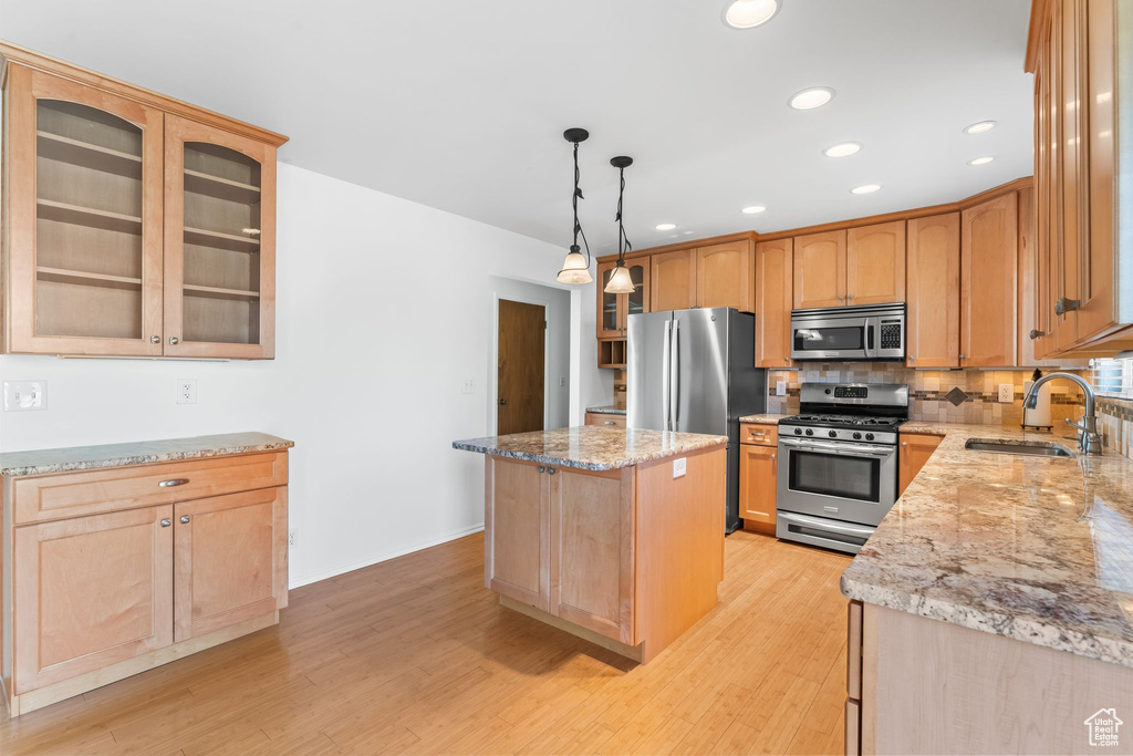 Kitchen with sink, appliances with stainless steel finishes, backsplash, and light hardwood / wood-style floors