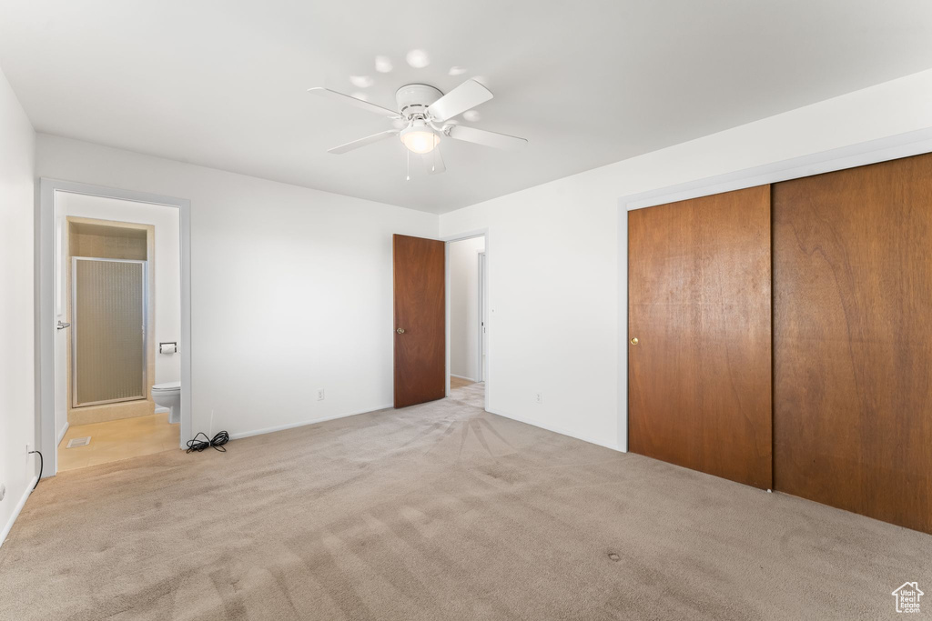 Unfurnished bedroom with a closet, ceiling fan, ensuite bathroom, and light colored carpet