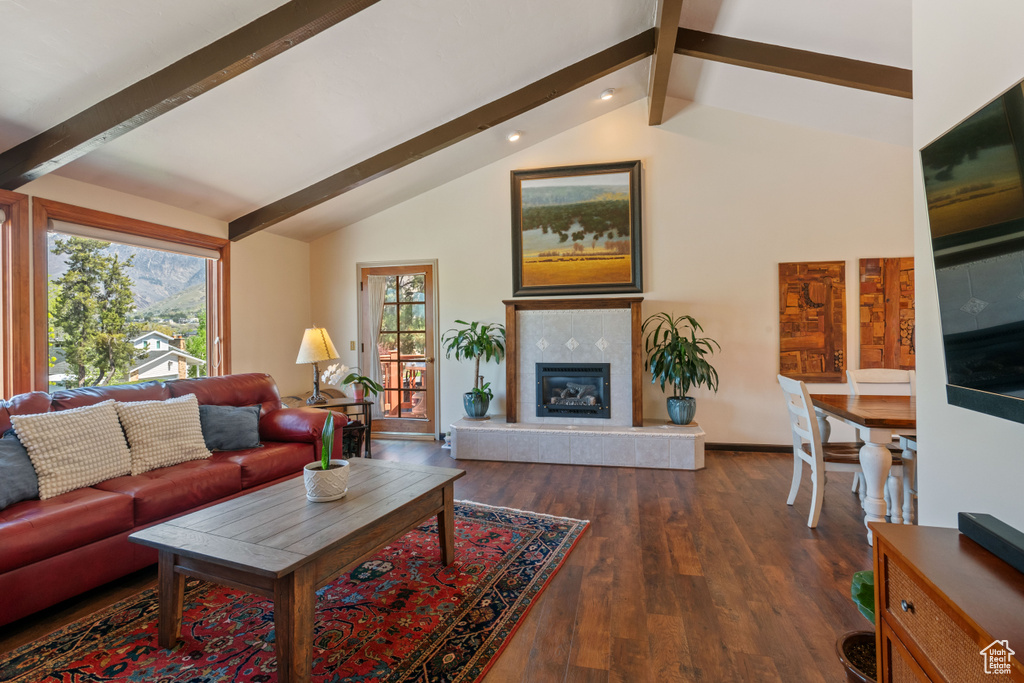 Living room featuring lofted ceiling with beams, dark wood-type flooring, and a fireplace