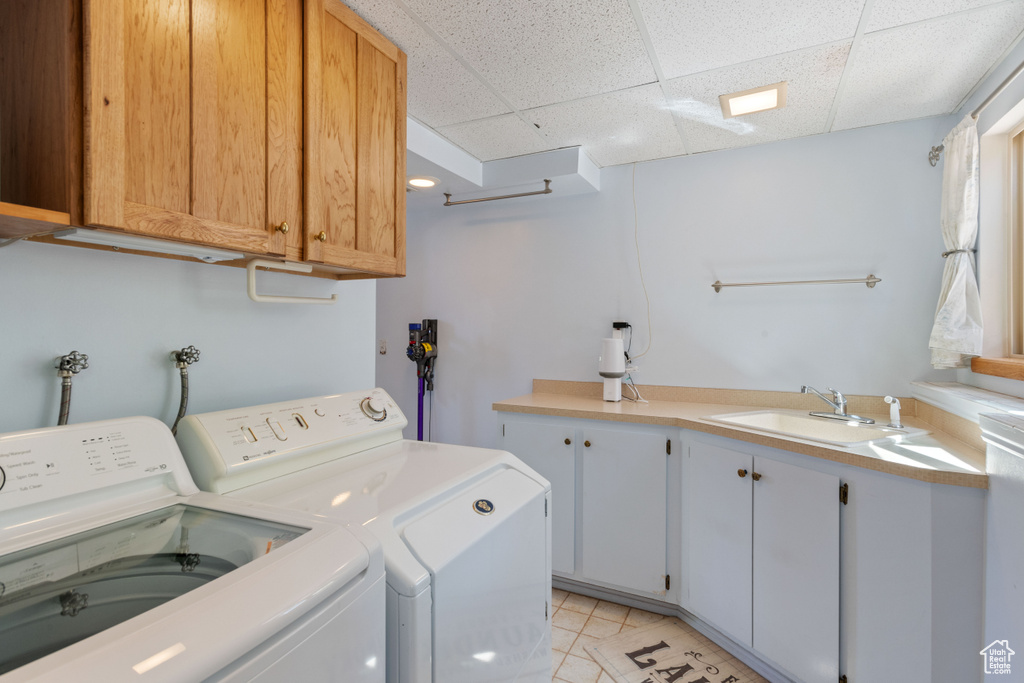 Laundry area featuring washing machine and dryer, cabinets, washer hookup, sink, and light tile floors