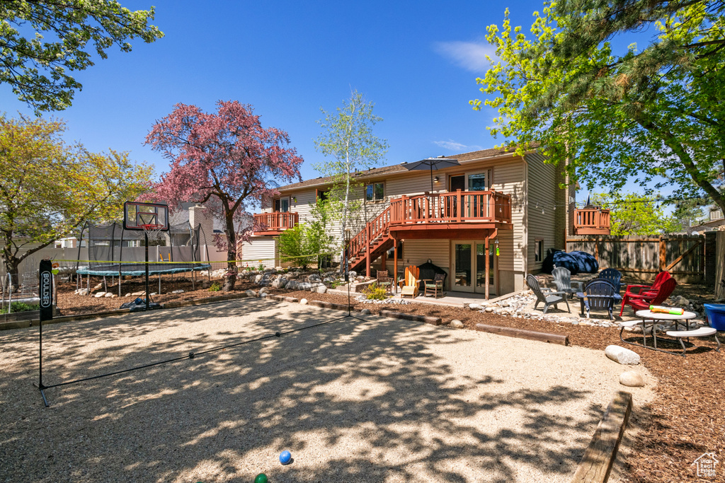 Rear view of property with a patio area, a wooden deck, and a trampoline